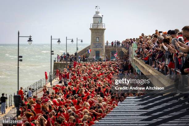 Hundreds of Kate Bush fans came together wearing red dresses on Folkestone's Harbour Arm to dance to her most iconic song, Wuthering Heights on the...