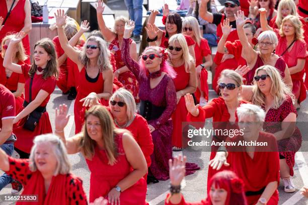 Hundreds of Kate Bush fans came together wearing red dresses on Folkestone's Harbour Arm to dance to her most iconic song, Wuthering Heights on the...