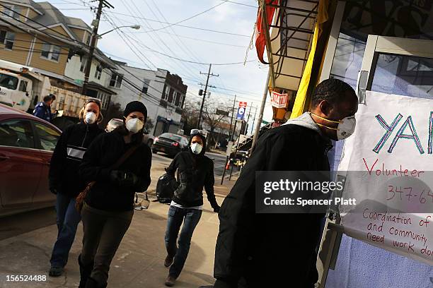 Volunteers in the clean-up effort walk through the streets in the heavily damaged Rockaway neighborhood where a large section of the iconic boardwalk...