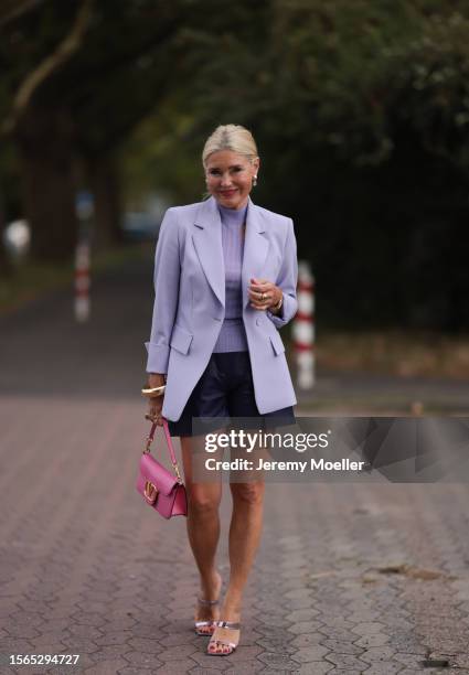 Petra Dieners is seen wearing a lilac blazer from Riani, underneath a lilac top with cut-outs from Riani, black leather shots from Riani, a pink bag...