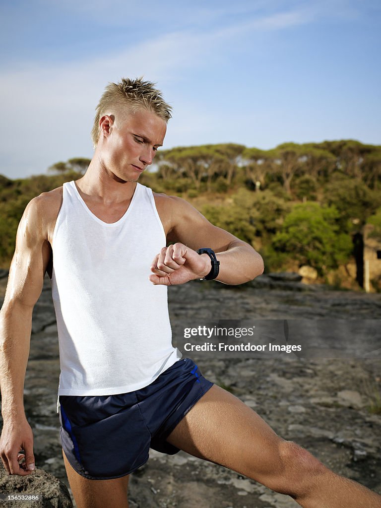 Young man stretching  while checking puls