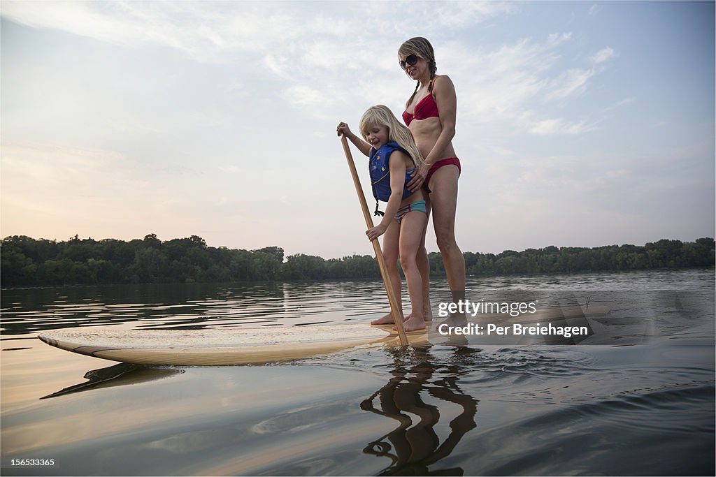 A mother and daughter paddle boarding