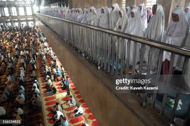 Muslim women in white gowns and veils pray on the balcony, separated from male worshippers during Friday prayers in Istiqlal mosque in Jakarta,...