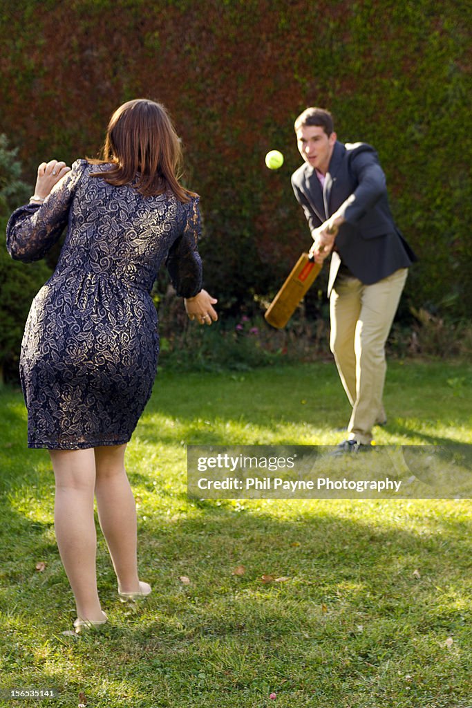 Young couple playing cricket in garden
