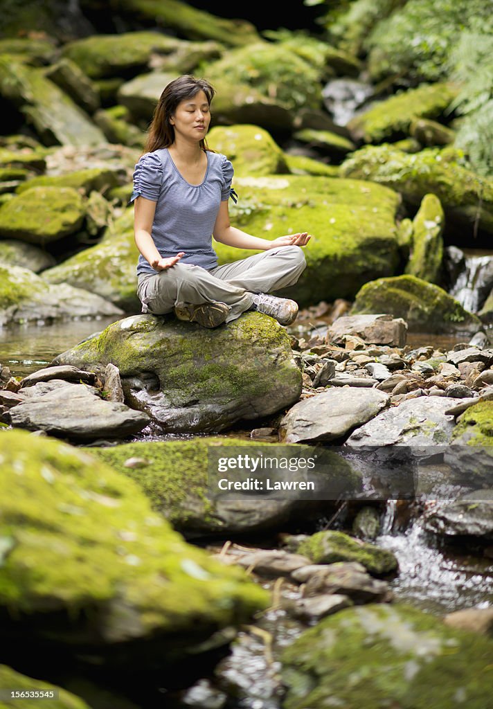 Young woman doing yoga meditation in deep forest