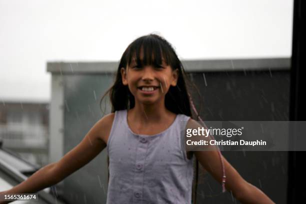 a mixed-race teenager feels raindrops on his face. - temps qu'il fait stock-fotos und bilder
