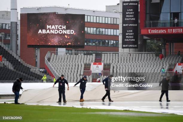 The groundstaff move the covers as the big screen displays that play has been abandoned at the LV= Insurance Ashes 4th Test Match between England and...