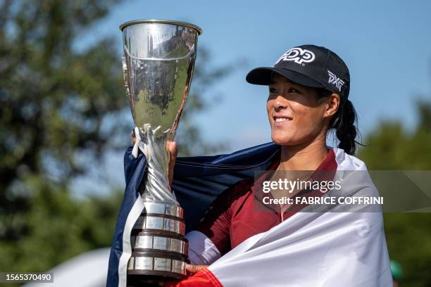 France's Celine Boutier, wrapped in a French flag, looks at her trophy after winning the Evian Championship, a women's LPGA major golf tournament in...