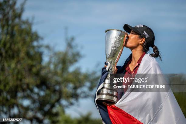 France's Celine Boutier, wrapped in a French flag, kisses her trophy after winning the Evian Championship, a women's LPGA major golf tournament in...