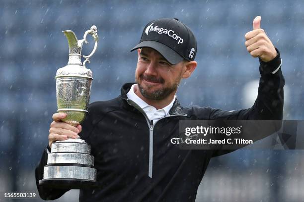 Brian Harman of the United States gestures a thumbs up as they carry the Claret Jug after winning The 151st Open on the 18th green on Day Four of The...