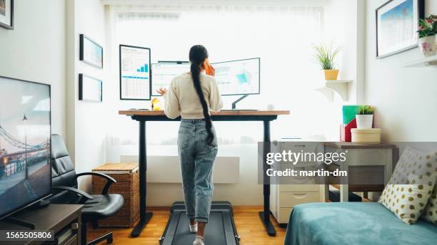 woman at home office is walking on under desk treadmill - treadmill test stockfoto's en -beelden