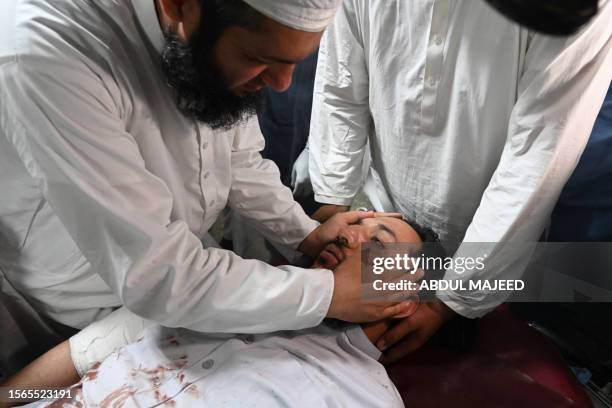 An injured man is comforted by a relative in a hospital in Peshawar on July 30 after at least 44 people were killed and dozens more wounded by a...