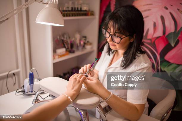 young cosmetician making clients nails done at professional beauty salon, manicure - complete body stock pictures, royalty-free photos & images