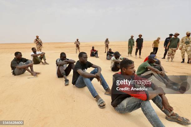 African irregular migrants stranded near the Libya-Tunisia border about 170 km from the capital Tripoli, await under high temperatures on July 30,...