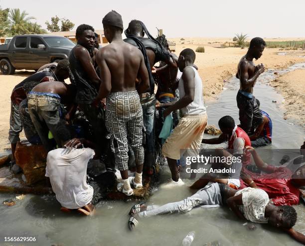 African irregular migrants stranded near the Libya-Tunisia border about 170 km from the capital Tripoli, await under high temperatures on July 30,...