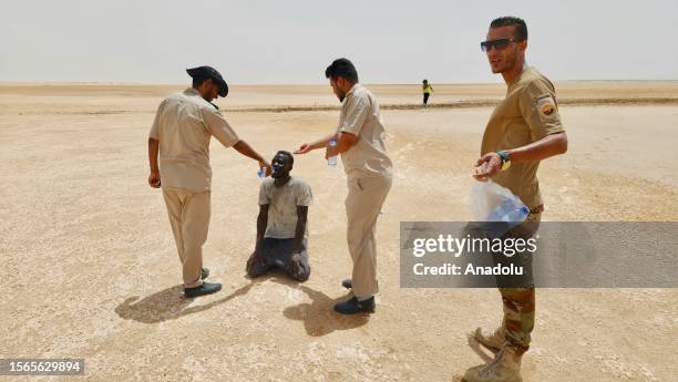 African irregular migrants stranded near the Libya-Tunisia border about 170 km from the capital Tripoli, await under high temperatures on July 30,...