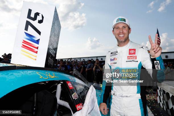 Denny Hamlin, driver of the Mavis Tires & Brakes Toyota, poses next to his winner sticker on his car in victory lane after winning the NASCAR Cup...