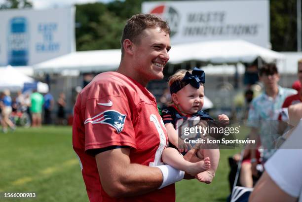 New England Patriots quarterback Mac Jones poses with a baby wearing his jersey during New England Patriots Training Camp on July 30 at the Patriots...