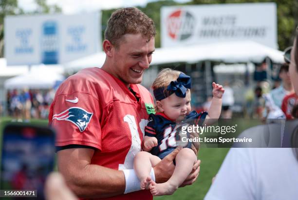 New England Patriots quarterback Mac Jones holds a baby wearing his jersey during New England Patriots Training Camp on July 30 at the Patriots...