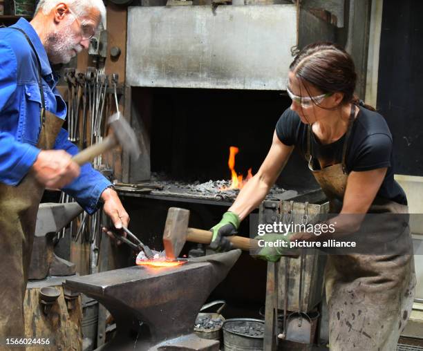 July 2023, Saxony, Hohenprießnitz: 39-year-old blacksmith and metal designer Marika Widdermann forges a lime leaf for a fruit bowl with her father...