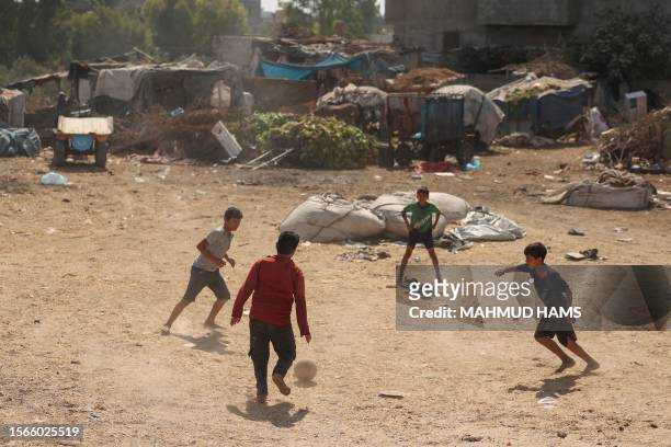 Palestinian youths play football outdoors in a poor neighbourhood in Gaza amid soaring temperatures and power cuts on July 31, 2023.
