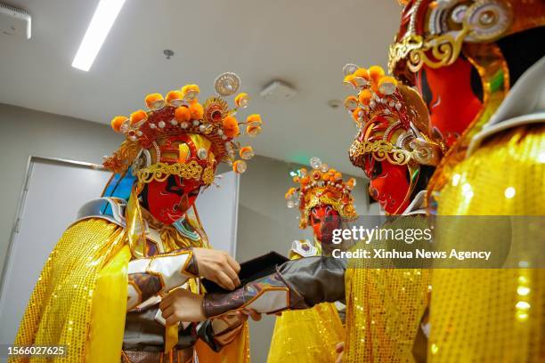 Ren Xin 1st L helps other "bian lian" performers check their costumes prior to an opening ceremony rehearsal in Chengdu of southwest China's Sichuan...