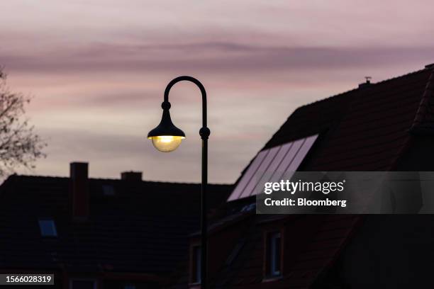 An illuminated street light and rooftop solar panels in a residential area near the Leuna refinery and chemical industrial complex in Leuna, Germany,...