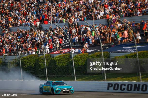 Denny Hamlin, driver of the Mavis Tires & Brakes Toyota, celebrates with a burnout after winning the NASCAR Cup Series HighPoint.com 400 at Pocono...