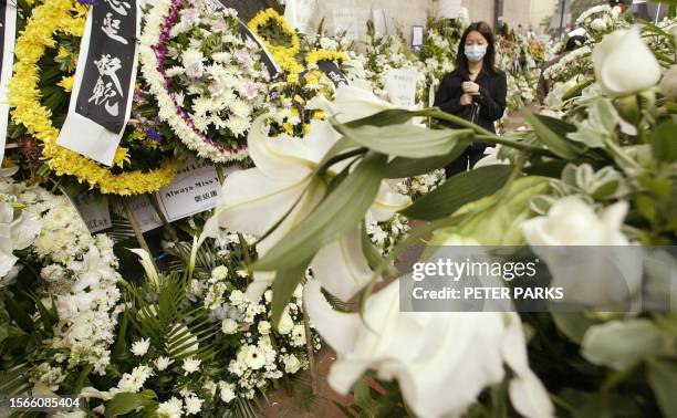 Mourner walks through flowers at the funeral service for Hong Kong actor and singer Leslie Cheung 08 April 2003. Stars packed the funeral fOR Cheung...