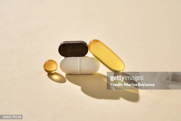 pills, vitamins and nutritional supplements on a beige background are folded in bizarre figures. - nutritional supplement stockfoto's en -beelden