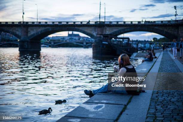 Young person browses a smartphone on the bank of the River Vltava at night in Prague, Czech Republic, on Sunday, July 30, 2023. The Czech economy is...