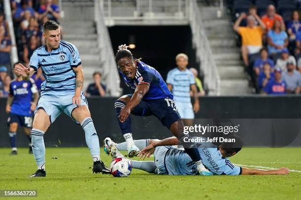 Sergio Santos of FC Cincinnati is tackled by Roger Espinoza of Sporting Kansas City during the second half of a Leagues Cup game at TQL Stadium on...