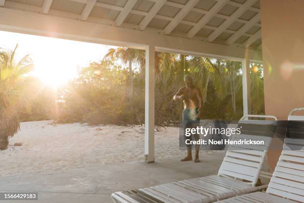 mature man wearing swim shorts applying sunscreen - cancerland 2019 bildbanksfoton och bilder
