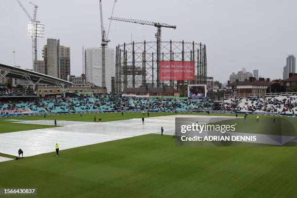 The covers protect the wicket as rain stops play at the start of the afternoon session on day five of the fifth Ashes cricket Test match between...