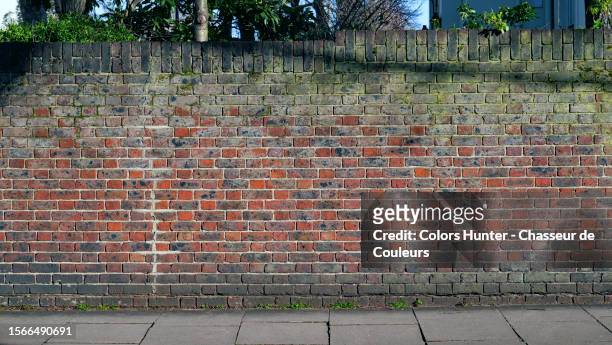 close-up of the perimeter wall of a garden and footpath in london, england, united kingdom - red wall stock pictures, royalty-free photos & images