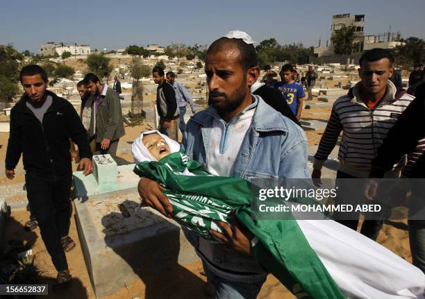 Palestinian man carries the body of his son Tamer Abu Sefan, three and a half years old, during a funeral in the village of Beit Lahia, in the...