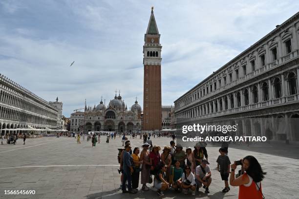 View taken on July 31, 2023 shows tourists taking a souvenir group photo at St. Mark's square in Venice. Unesco is recommending that Venice be placed...