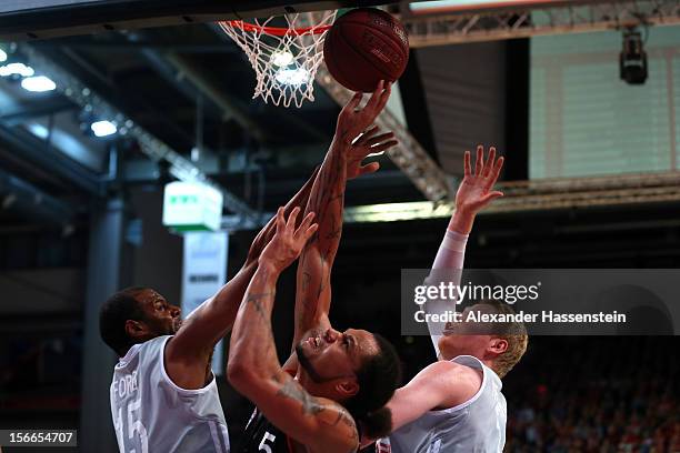 Chevon Troutman of Muenchen shoots against Sharrod Ford of Bamberg and his team mate Philipp Neumann during the Beko Basketball match between Brose...