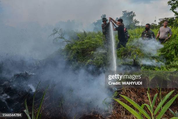 Members from a joint task force in anticipation of forest and land fires extinguish a fire at a peatland in Pekanbaru of Riau province on July 31,...