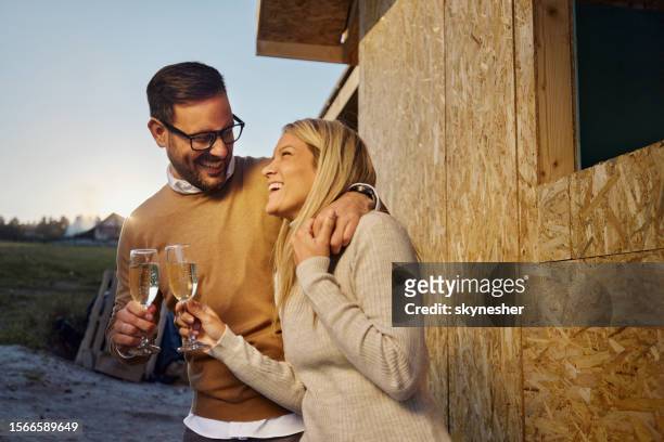 happy couple toasting in front of built structure. - champagne stock pictures, royalty-free photos & images