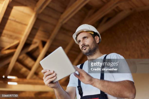 vue ci-dessous d’un ouvrier manuel pensif utilisant un pavé tactile sur un chantier de construction. - artisan photos et images de collection