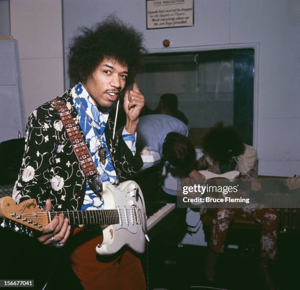 American guitarist Jimi Hendrix of The Jimi Hendrix Experience, in a London recording studio, October 1967. In the background is bassist Noel Redding...