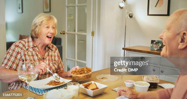 food, funny and a senior couple eating dinner in their home together in celebration of their anniversary. retirement, love or smile with an elderly man and woman laughing at the dining room table - day anniversary stock pictures, royalty-free photos & images