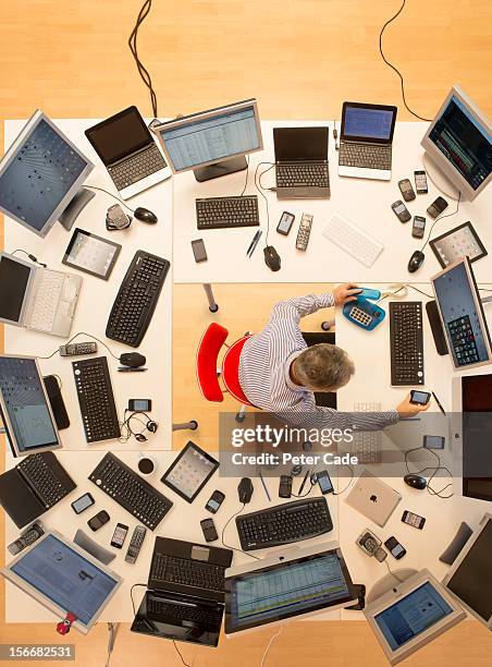 man surrounded by desks and computers - multitasking stock-fotos und bilder