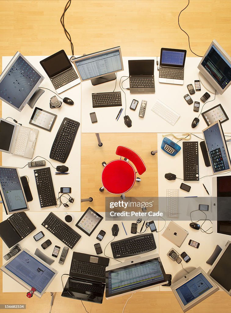 Red chair surrounded by desks covered in computers