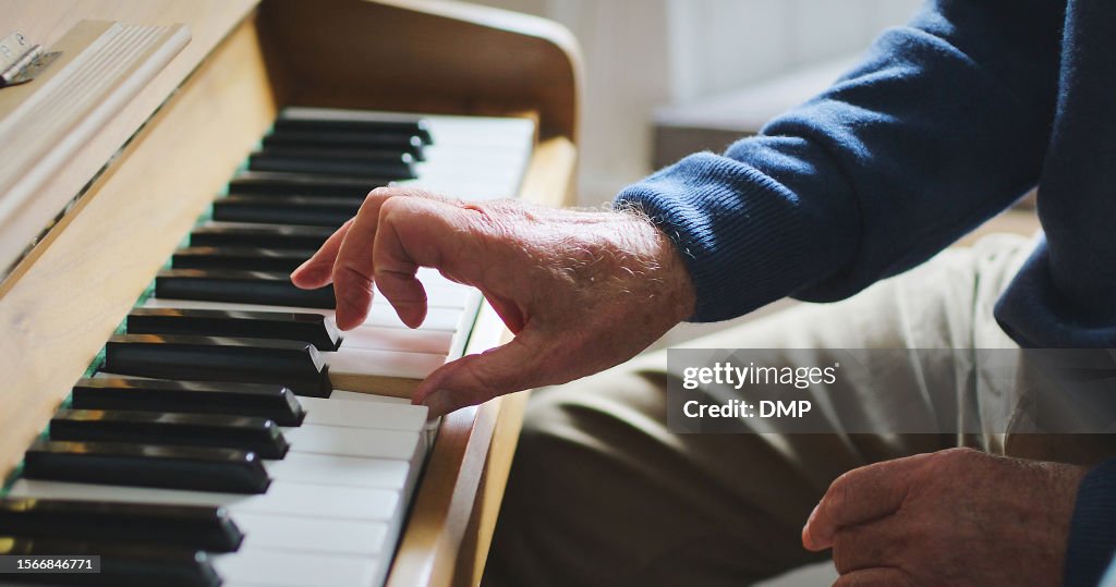 Hands, music and playing the piano at home for performance, hobby or to relax in a room. Closeup of senior person with old or vintage instrument with keys, notes or keyboard at a house in retirement