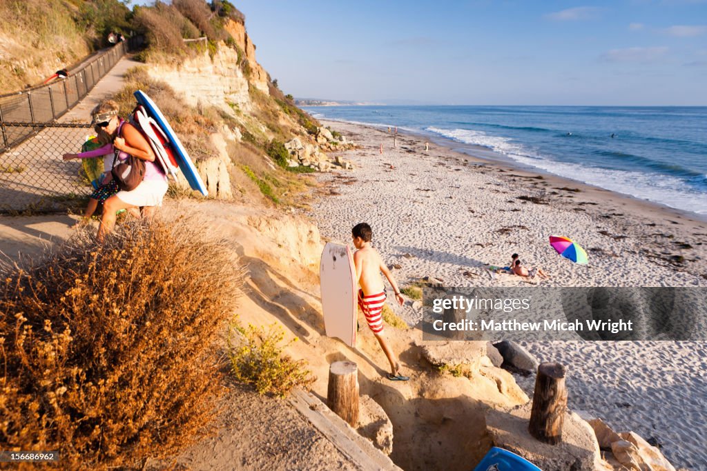 A family packs up and hikes up from the beach