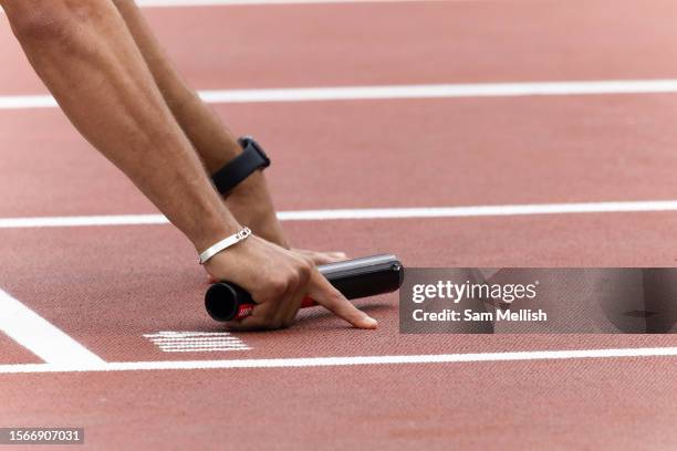 The hand of Adam Gemili of Great Britain on the start blocks holding a relay baton ahead of the Mens 4x100m relay during the London Athletics Meet,...