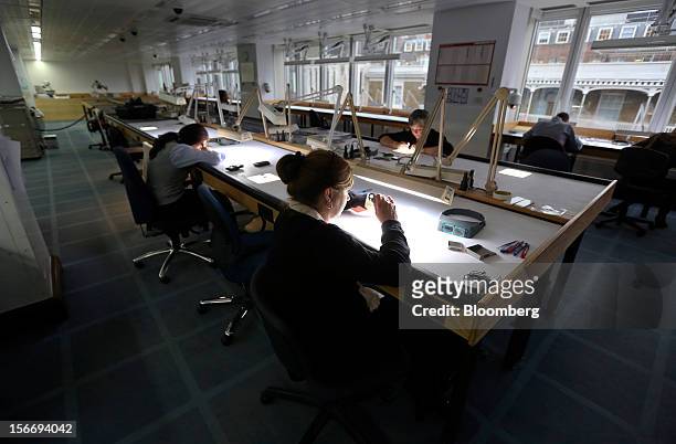 Employees use angled lights and magnifying glasses to sort uncut diamonds at the De Beers office in London, U.K., on Friday, Nov. 16, 2012. De Beers,...
