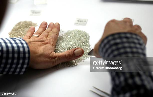 An employee gathers a pile of uncut diamonds ready for grading in this arranged photograph at the De Beers office in London, U.K., on Friday, Nov....